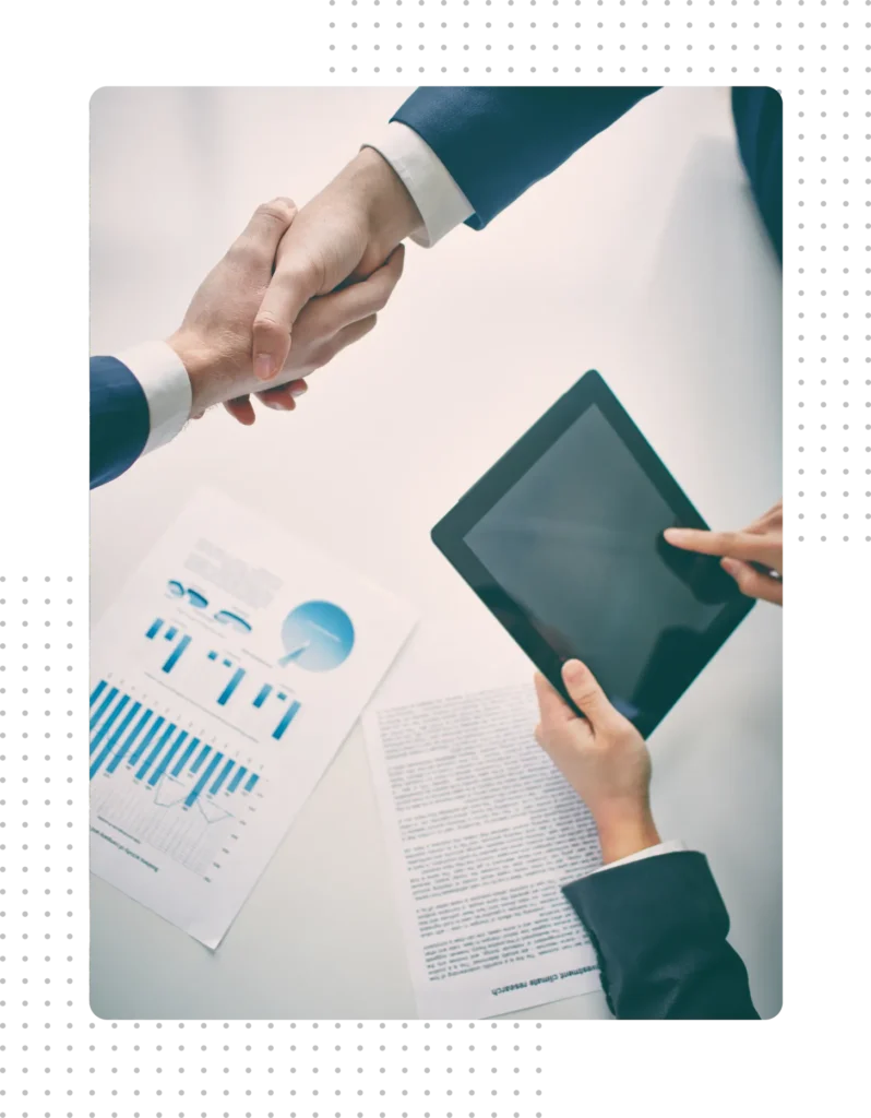 Top-down view of board members shaking hands across a table featuring a tablet and data-driven association reports.