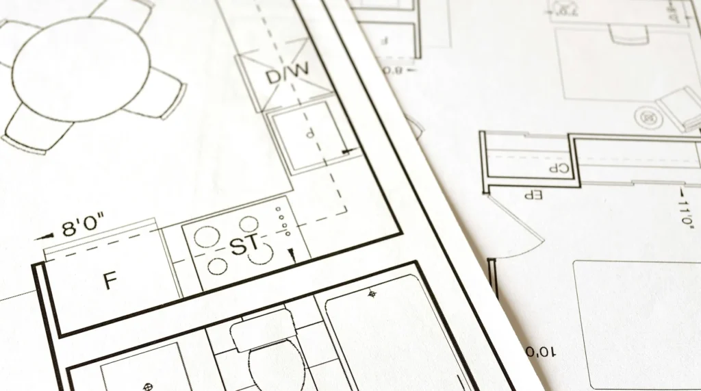 A close-up, top-down view of detailed architectural floor plans and blueprints, representing HOA architectural review processes and community compliance standards.