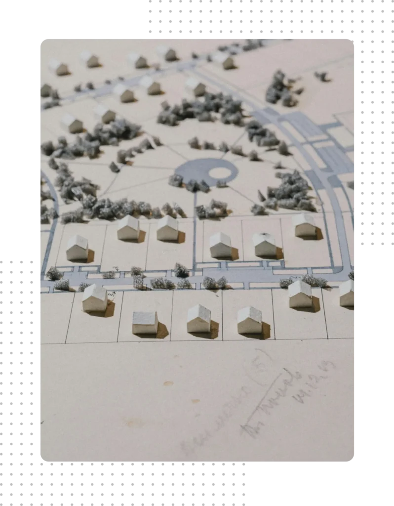 A detailed architectural model of a residential development featuring miniature white houses and green spaces, representing community planning and developer governance foundations.