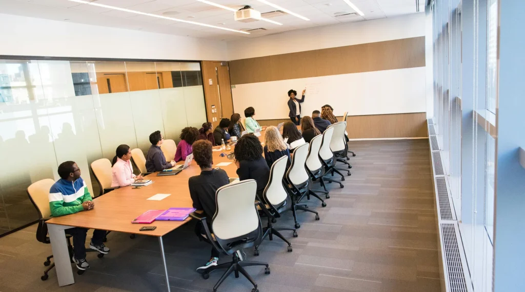 An HOA consultant leading a board training and orientation session in a modern conference room, presenting governance frameworks to a group of directors on a whiteboard.